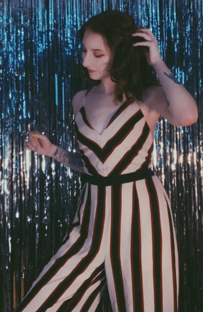 Portrait photograph of lizzie wearing rented stripy black white and red jumpsuit posing with one hand in hair